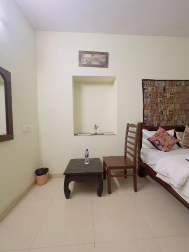 a bedroom with a bed and a chair and a table at Relax Inn Jaisalmer in Jaisalmer