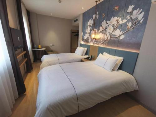 two beds in a hotel room with a painting on the wall at Jinjiang Inn Tianjin Station Jinwan Square in Tianjin