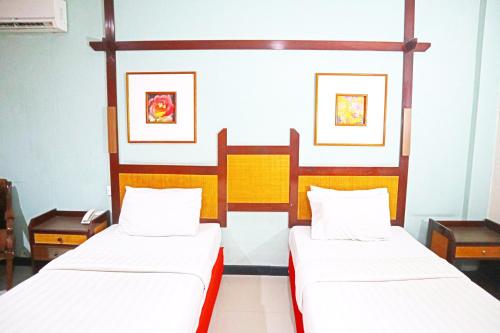 two beds in a room with two beds sidx sidx sidx at PLUM Prestige Hotel Juanda in Kalangan