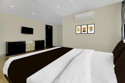 a white and black bedroom with a bed and a tv at Super Townhouse Chakan MIDC Pune Formerly Renuka Executive in Chakan