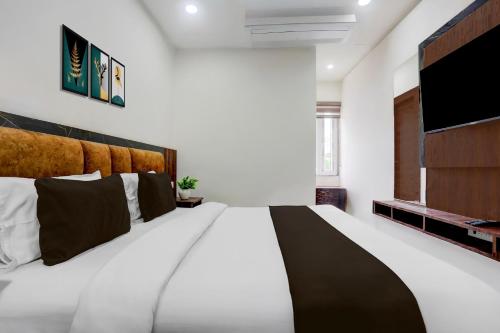 a bedroom with a large bed and a flat screen tv at Super Townhouse Bela Road Varanasi City Railway Station Formerly Srijan Grand in Varanasi