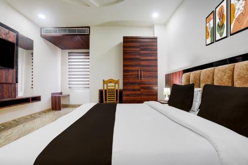 a bedroom with a large bed and a wooden door at Super Townhouse Bela Road Varanasi City Railway Station Formerly Srijan Grand in Varanasi
