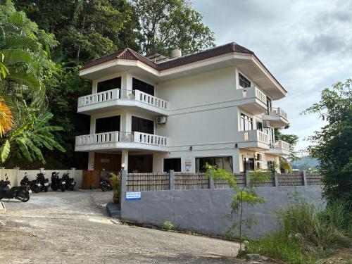 une maison blanche avec des motos garées devant elle dans l'établissement Riviera Patong, à Patong Beach