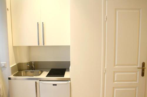 Il comprend une petite cuisine avec un évier et une armoire blanche. dans l'établissement Rue d'Argenteuil VII - Palais Royal, à Paris