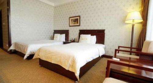 a hotel room with two beds and a lamp at Datong Tiangui International Hotel in Datong