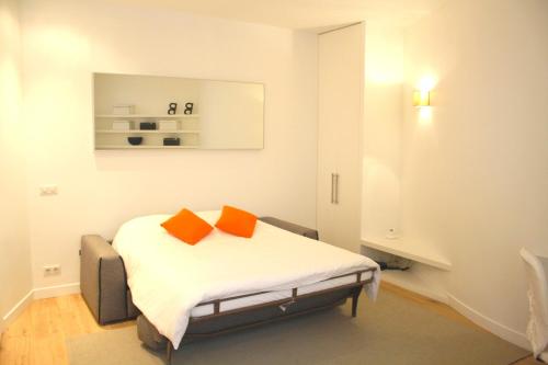 - une chambre dotée d'un lit avec deux oreillers orange dans l'établissement Rue d'Argenteuil VII - Palais Royal, à Paris