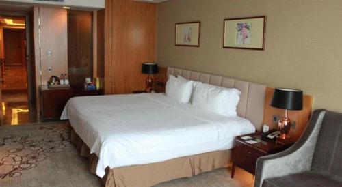 a hotel room with a large bed and a chair at Zhangjiagang Zhonglian GDH International Hotel in Zhangjiagang