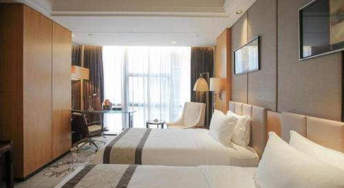a hotel room with two beds and a desk at Zhangjiagang Zhonglian GDH International Hotel in Zhangjiagang