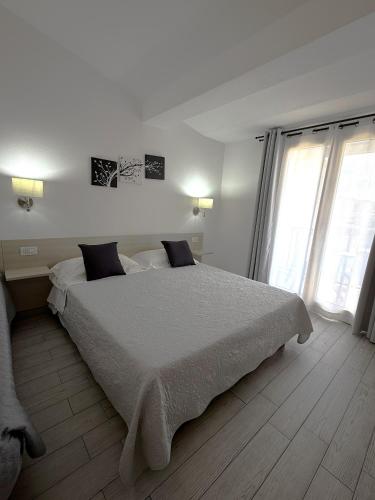 a white bedroom with a large bed and two windows at Bentus B&B in Villasimius