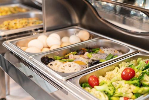 a buffet line with trays of vegetables and eggs at 希岚酒店广州富力海珠城店&地铁直达展馆 in Guangzhou