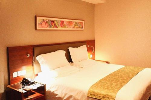a hotel room with a large bed with white sheets at Yitel Collection Lianyungang High-speed Railway Station Suning Plaza in Lianyungang