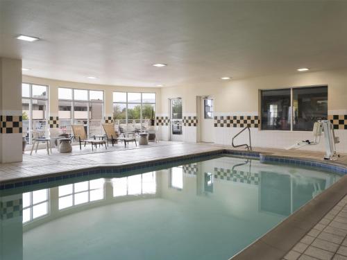 a swimming pool with tables and chairs in a building at Hilton Garden Inn Albuquerque Airport in Albuquerque