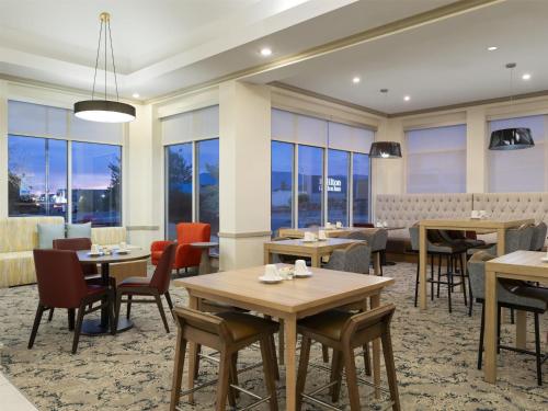 a restaurant with tables and chairs and windows at Hilton Garden Inn Albuquerque Airport in Albuquerque