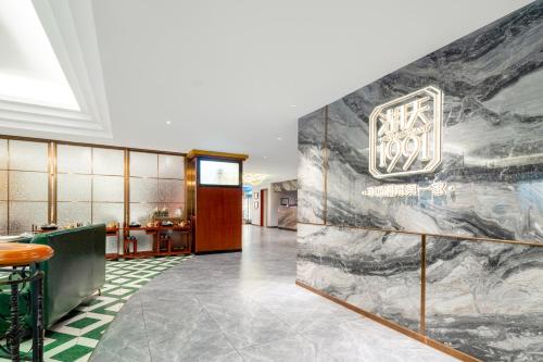 a lobby with a marble wall with a sign on it at Guangzhou Hutian Hotel in Guangzhou