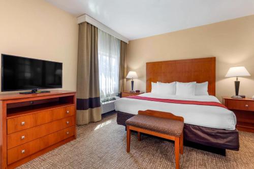 a hotel room with a bed and a flat screen tv at Comfort Suites North Dallas in Dallas