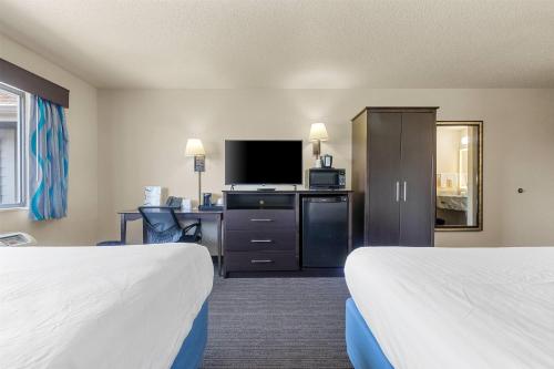 a hotel room with two beds and a flat screen tv at AmericInn by Wyndham Green Bay East in Green Bay