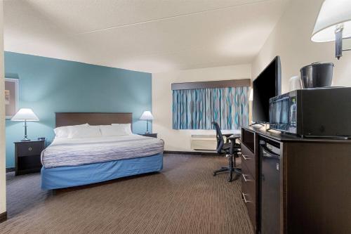 a hotel room with a bed and a flat screen tv at AmericInn by Wyndham Green Bay East in Green Bay