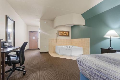 a hotel room with a bed and a desk and a tub at AmericInn by Wyndham Green Bay East in Green Bay