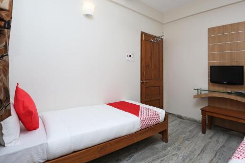 a bedroom with a bed and a desk and a television at Hotel O Vijay Palace in Bhopal