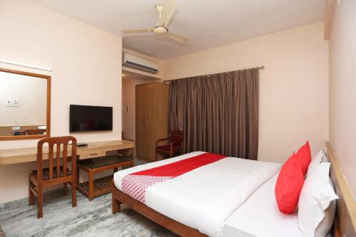 a hotel room with a bed and a desk and a television at Hotel O Vijay Palace in Bhopal
