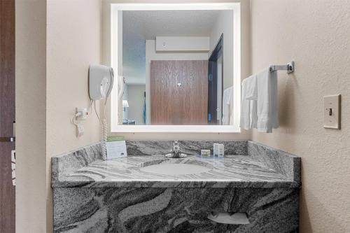 a bathroom with a marble sink and a mirror at AmericInn by Wyndham Green Bay East in Green Bay