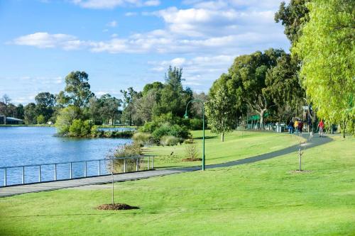 a park with green grass and a river and trees at Quality Hotel Lakeside in Bendigo