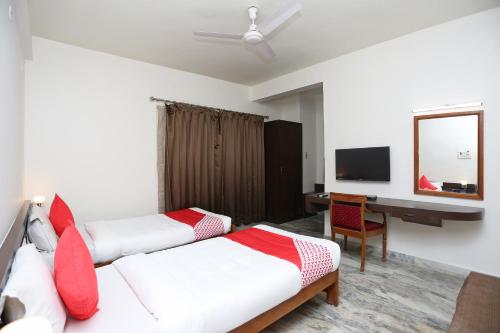 a bedroom with two beds and a desk and a mirror at Hotel O Vijay Palace in Bhopal