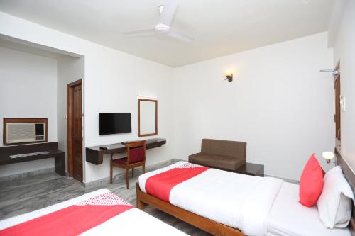 a bedroom with two beds and a desk with a computer at Hotel O Vijay Palace in Bhopal