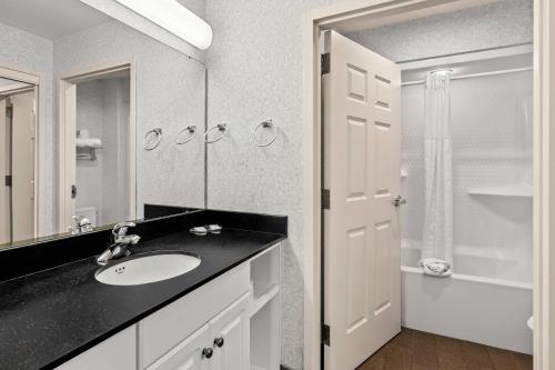 a bathroom with a sink and a mirror and a shower at MainStay Suites Roanoke Airport in Roanoke