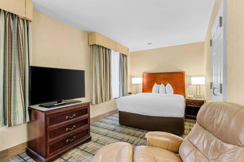 a hotel room with a bed and a flat screen tv at MainStay Suites Roanoke Airport in Roanoke