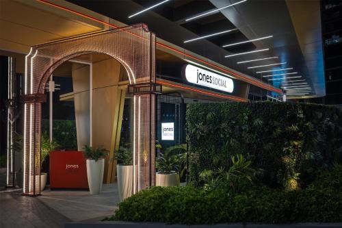 a sign in a building with plants in front of it at Embassy Suites By Hilton Dubai Business Bay in Dubai