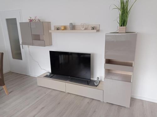 a living room with a flat screen tv on a white wall at Work and Stay Plettenberg 6 Betten Dusche Küche Balkon Garten in Plettenberg