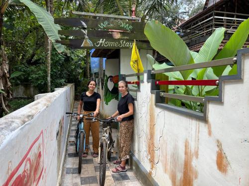 two women standing next to a bike in front of a building at Munroeisland Backwaters Homestay in Munroe Island