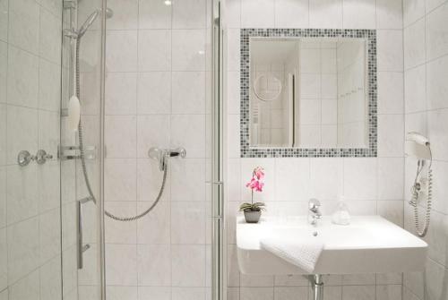 a white bathroom with a sink and a shower at Hotel Haus am Park in Bad Homburg vor der Höhe