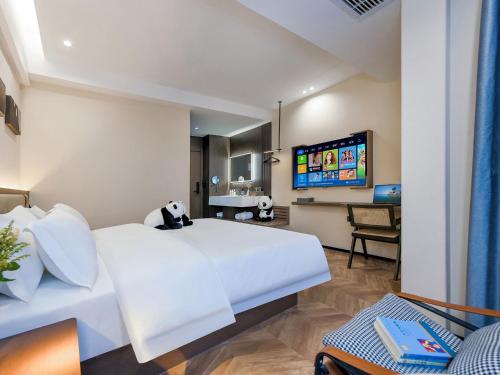 a bedroom with a large white bed and a tv at 成都锦禧悦庭酒店宽窄巷子店 in Chengdu