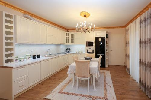a kitchen with white cabinets and a table with chairs at Said's Luxury Apartment in Berat
