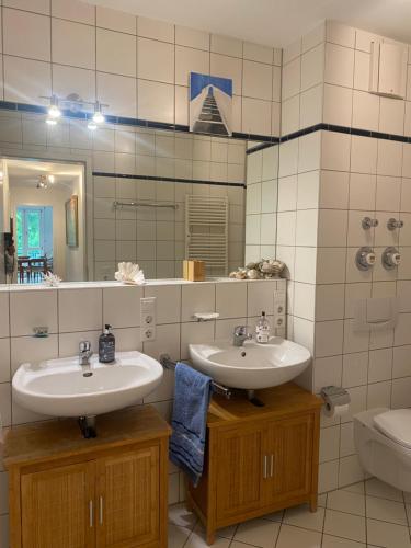 a bathroom with two sinks and a toilet and a mirror at Helle Wohnung am Waldpark in Dresden
