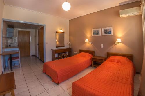 2 Betten in einem Hotelzimmer mit orangefarbener Bettwäsche in der Unterkunft Chryssi Akti Hotel in Argassi