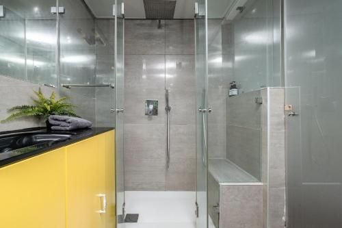 a shower with a glass door in a bathroom at Boutique Duplex 3BR Florentin in Mashabbe Sade
