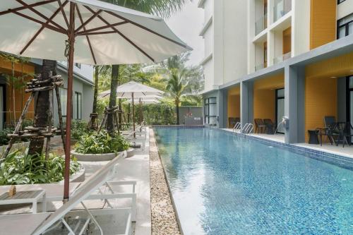 a swimming pool with chairs and an umbrella next to a building at Wyndham Gardens Elegant Studio Forrest View 2228 in Nai Thon Beach