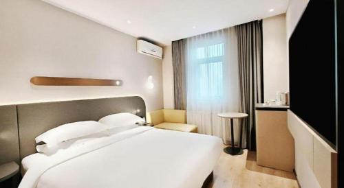 a bedroom with a large white bed and a window at Jinjiang Inn Changchun Xi An Avenue Branch in Changchun