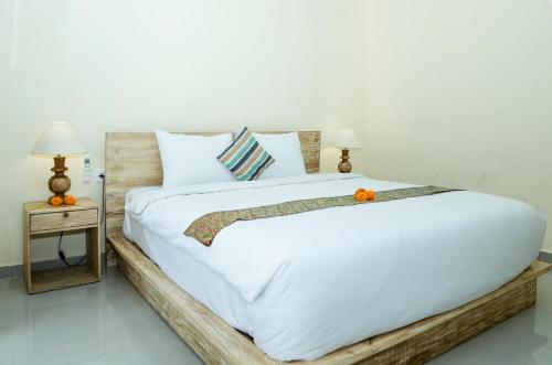 a bedroom with a large white bed with a wooden frame at Vaneka Garden House in Ubud