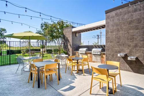 a patio with tables and chairs and a grill at Home2 Suites by Hilton Irving/DFW Airport North in Irving
