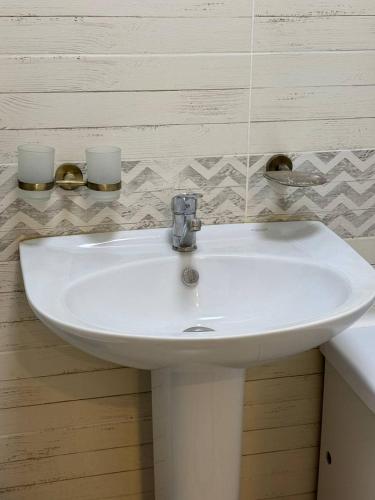 a white bathroom sink with two candles on the wall at Near Khan Shatyr in Astana