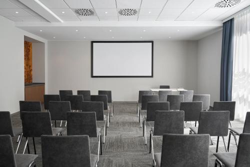 a conference room with chairs and a blank screen at Four Points Flex by Sheraton Göttingen in Göttingen