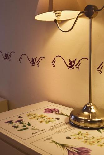 a lamp sitting on a table next to a table with flowers at Barcolana Lodge Hostel in Trieste