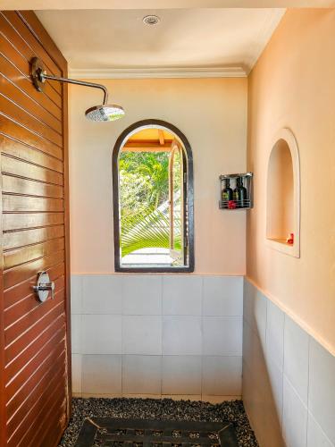 a bathroom with an arched window and a shower at Villa Talia Vashti - Oceanfront villa with Private Sea Access, Pool & Cook in Candidasa