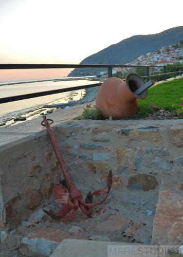 a red anchor on a wall next to the ocean at Mare Studios Exclusive in Plomarion