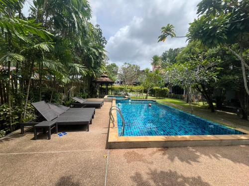 a swimming pool in a yard with benches and trees at Moubillow Resort in Ao Nang Beach