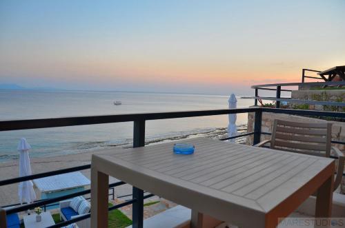 a picnic table on a balcony overlooking the beach at Mare Studios Exclusive in Plomarion
